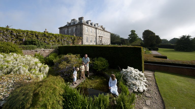 Visitors looking into the pond in the garden at Antony, Cornwall